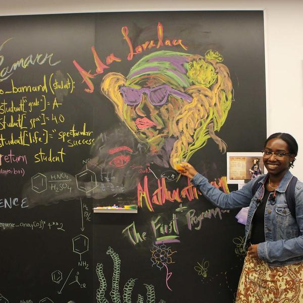 Young Black woman pointing at a colorful chalkboard portrait